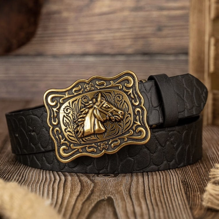 Black leather belt with a decorative gold horse buckle on a wooden surface.
