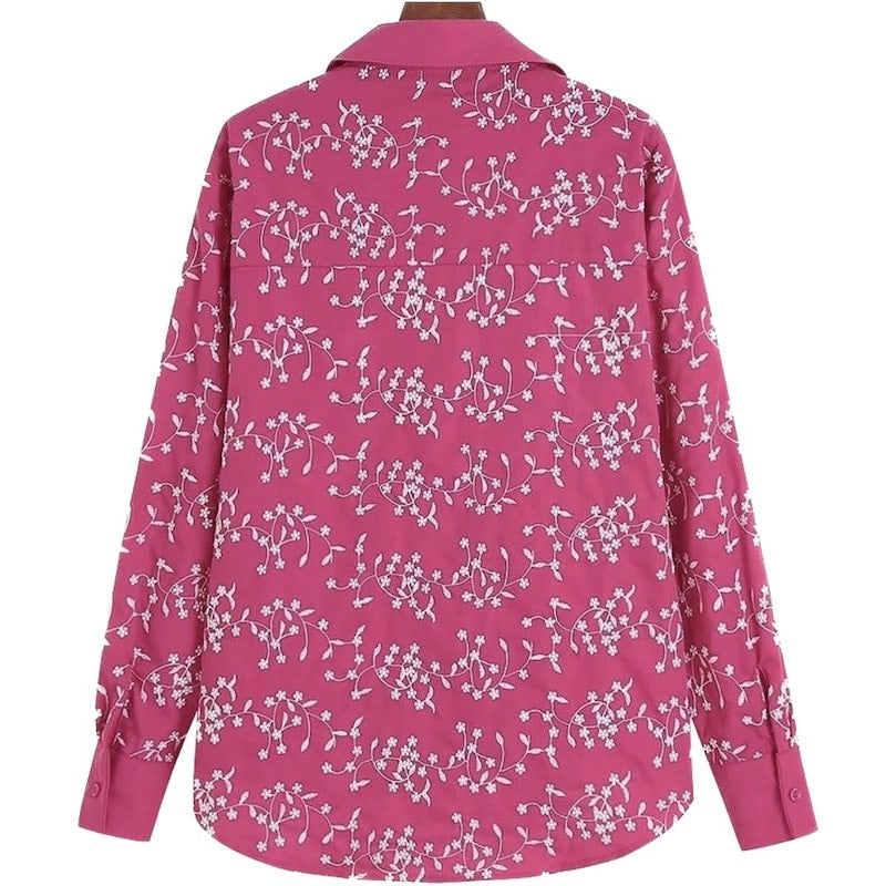 Back of a pink button-down shirt with white floral embroidery.