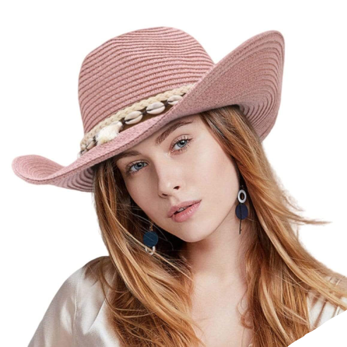 Close-up of a woman wearing a pink straw cowboy hat with shell embellishments, paired with navy and silver geometric earrings.