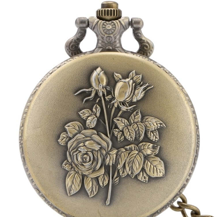 Close-up of a brass-colored pocket watch with a raised floral design.
