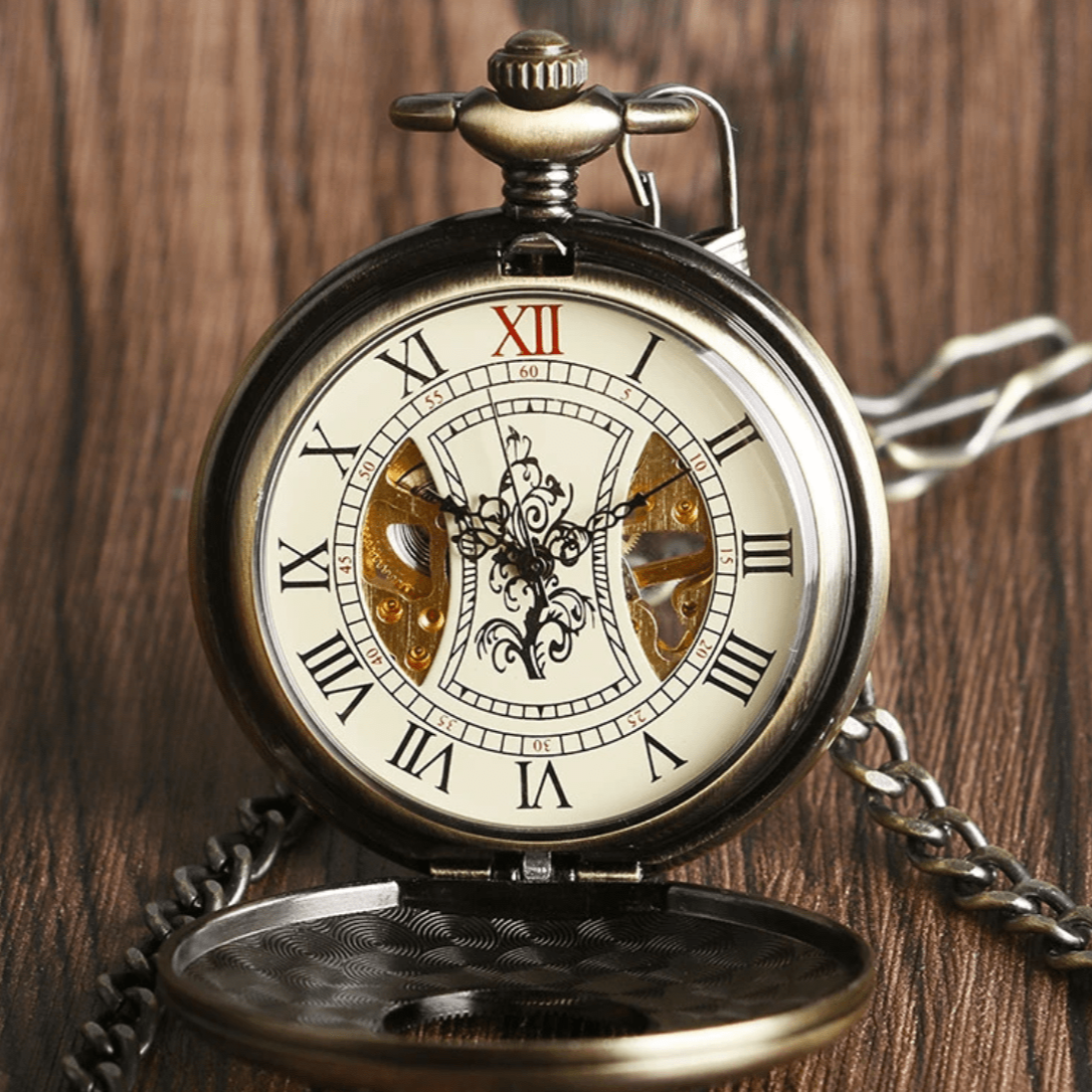 Close-up of an open antique bronze-toned pocket watch with a chain on a wooden surface.