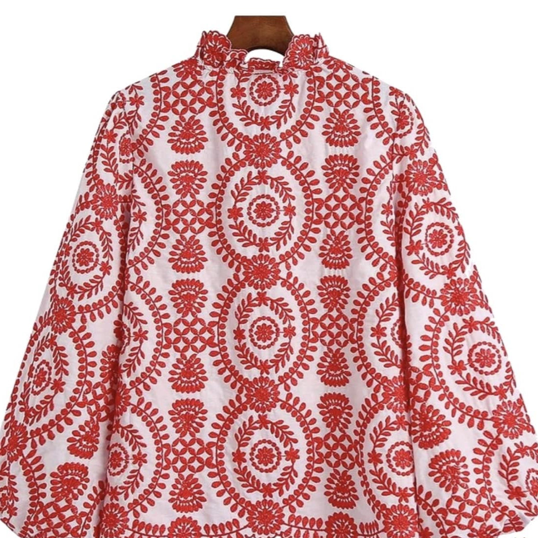 White blouse with red floral embroidery.