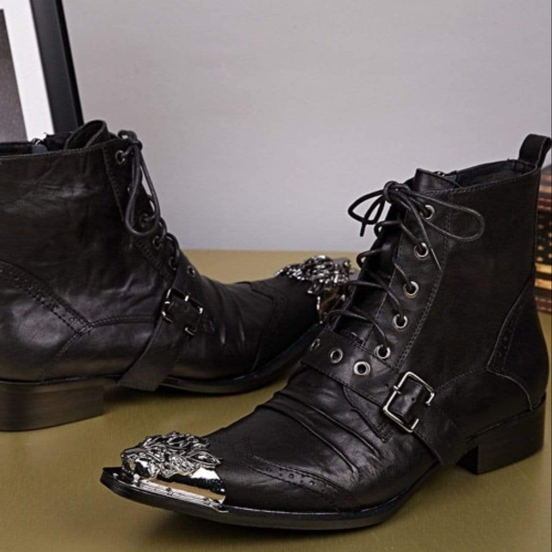 Two black leather ankle boots with buckles and metal toe caps on a table.