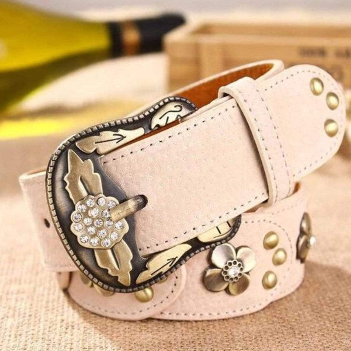 Beige belt with metallic floral accents and rhinestone buckle.