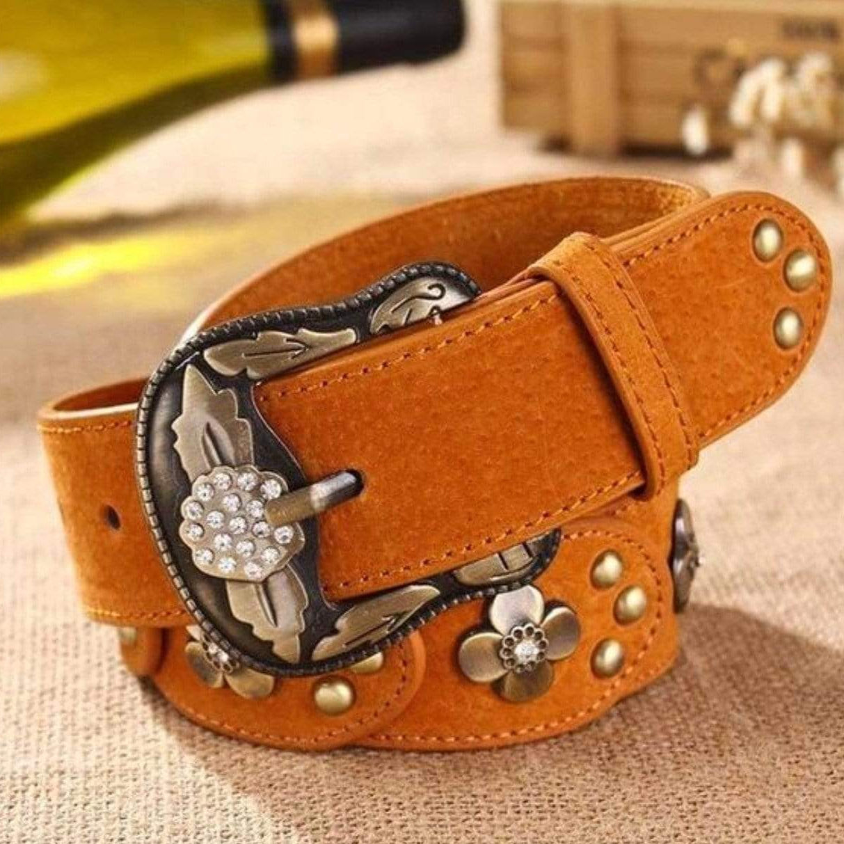 Close-up of a brown leather belt with an ornate silver and rhinestone buckle.