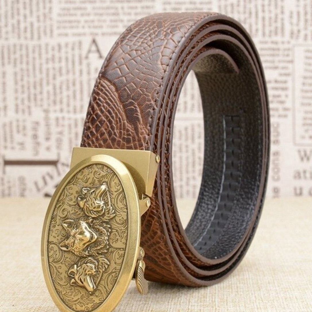 Close up of a brown belt with an oval gold buckle featuring three wolf heads.
