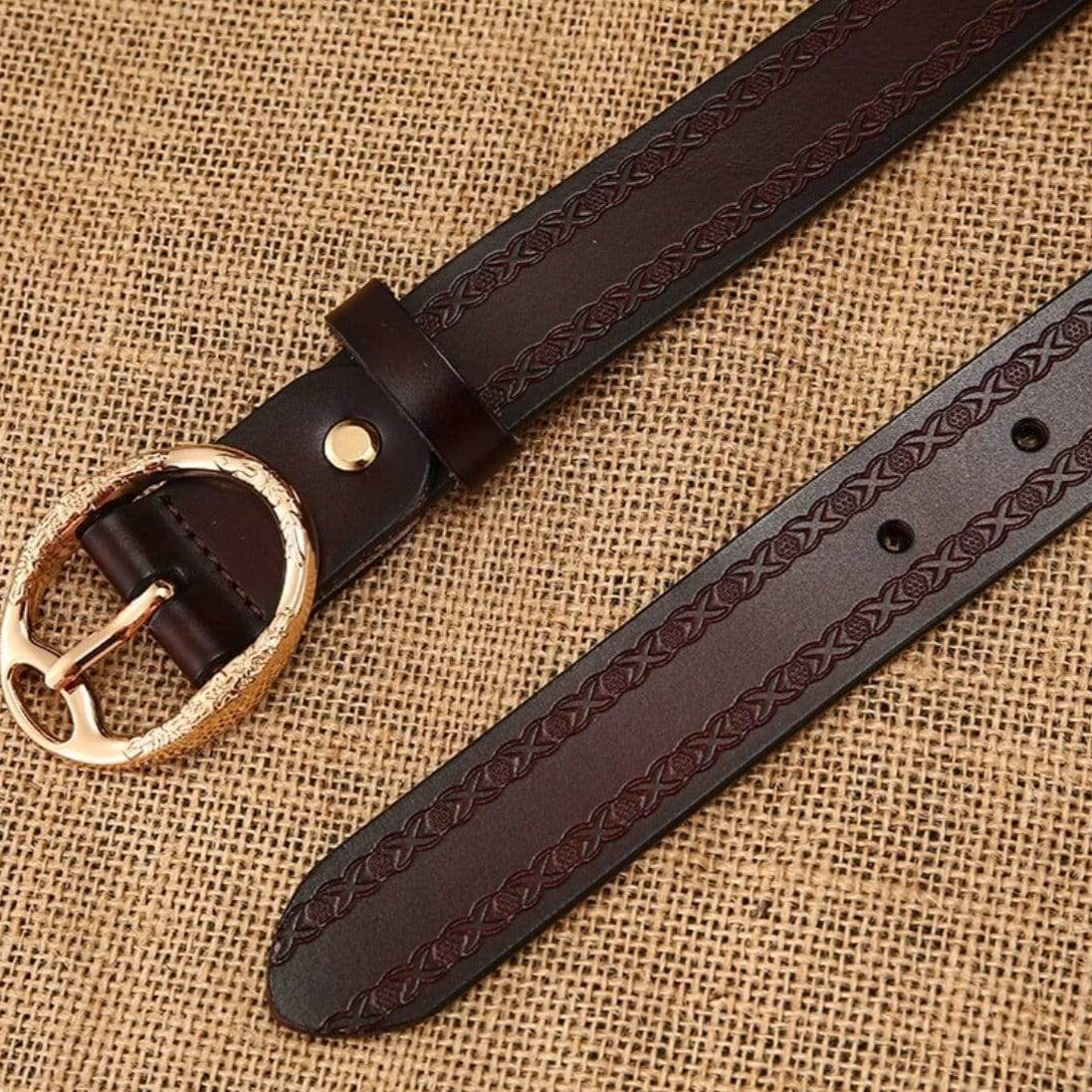 Close-up of a brown leather belt with a decorative gold buckle on a burlap background. 
