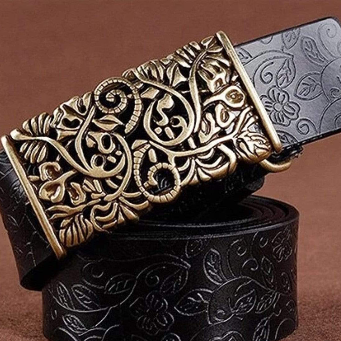 Close-up of a black leather belt with an ornate gold-colored buckle and floral embossing.