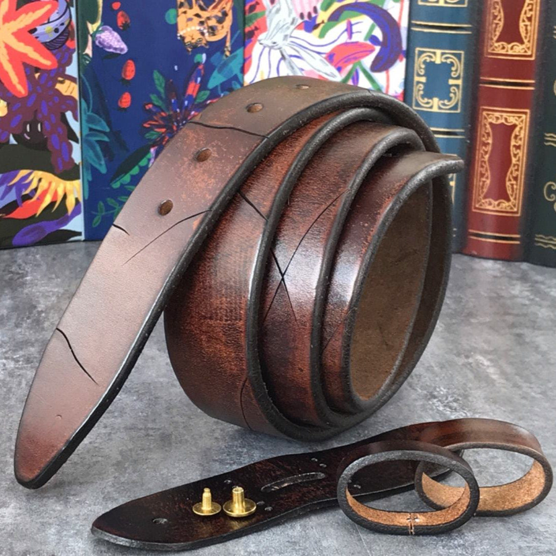 A brown leather belt with brass studs on a grey surface, backed by books.