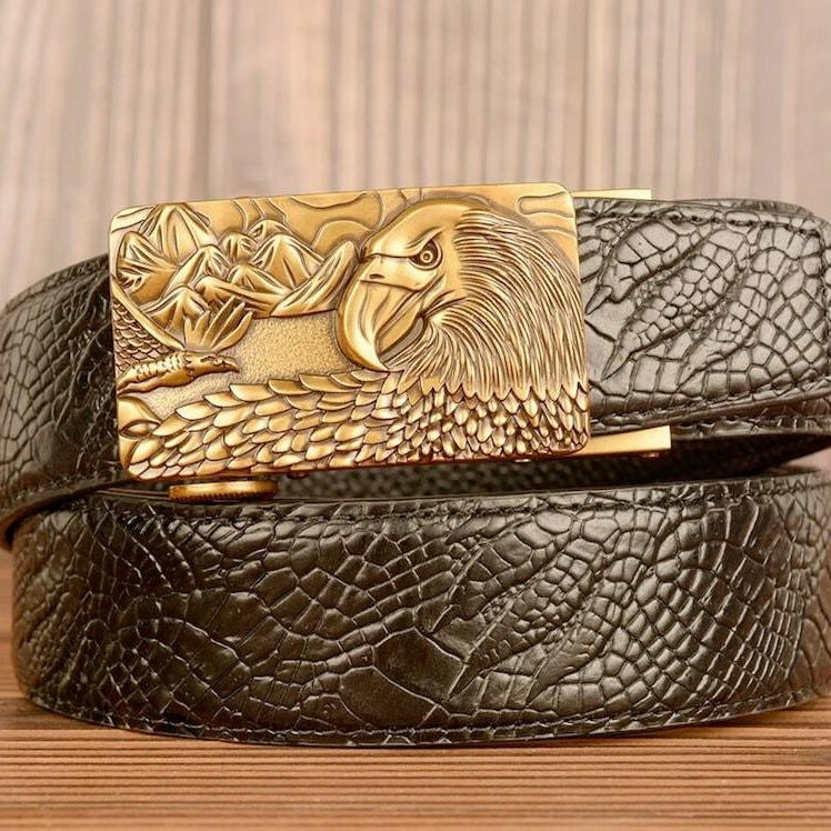 Close-up of a black, textured leather belt with a gold buckle featuring an eagle and mountains.