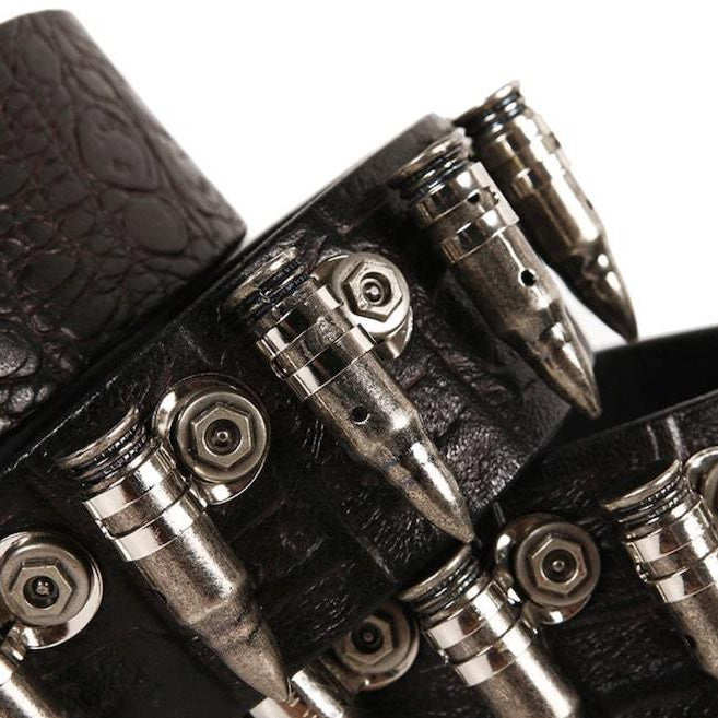 Close-up of a black leather bracelet decorated with silver bullet-shaped charms. 
