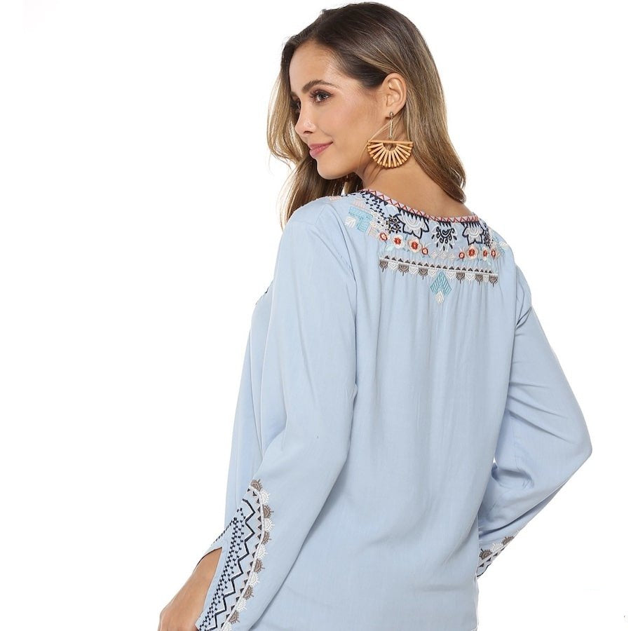 Woman wearing a light blue embroidered blouse.