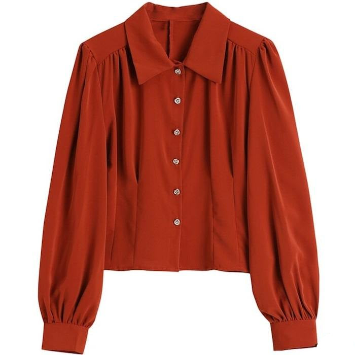 Rust-colored button-up blouse with long, gathered sleeves and a pointed collar.
