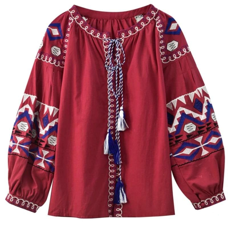 Red blouse with embroidered details, tassels, and tie neckline.
