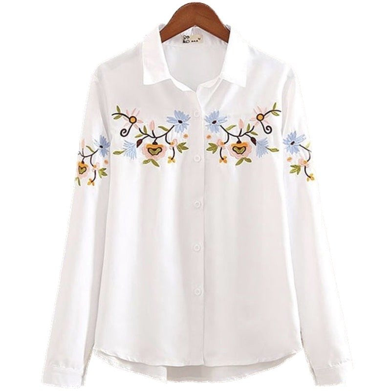 White embroidered shirt on a wooden hanger.