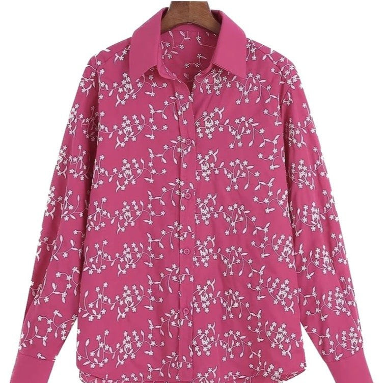 Pink, floral print, long-sleeved blouse on a hanger.
