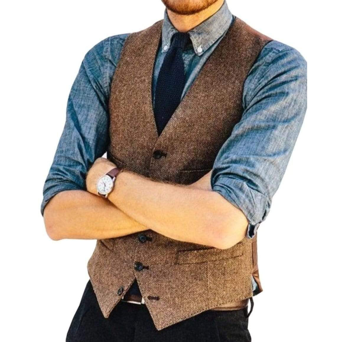 Man in brown tweed vest, blue shirt, dark tie, and watch with arms crossed.