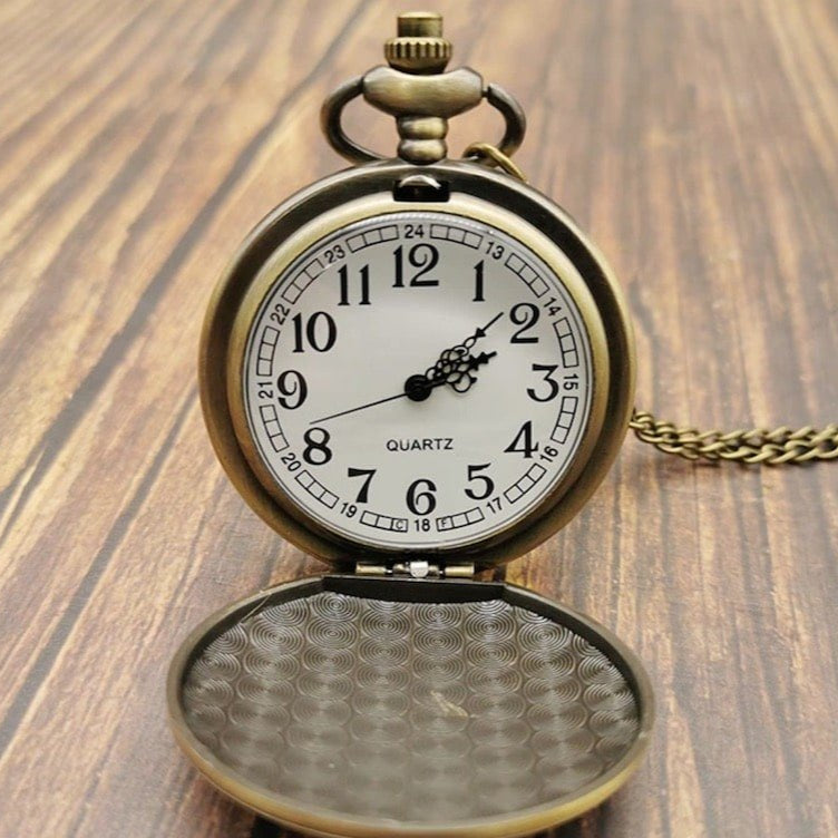 Close-up of an open antique pocket watch on a wooden surface.