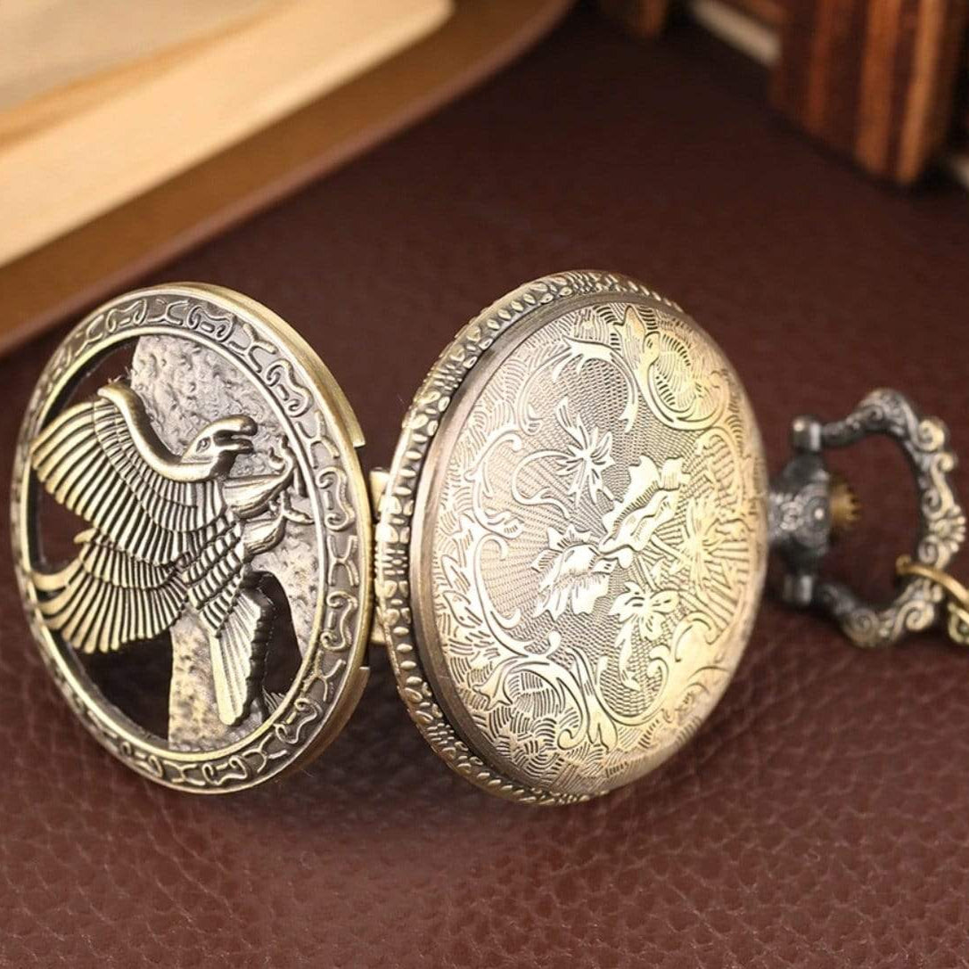 Open bronze pocket watch with eagle motif and floral design.
