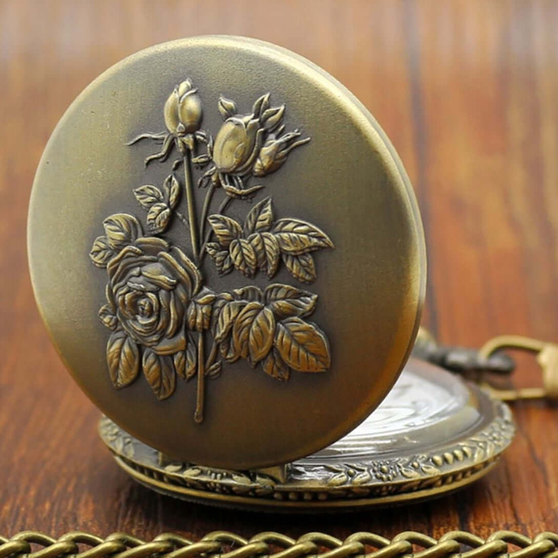 Antique brass pocket watch with floral design.
