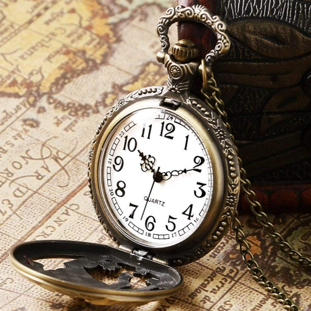 Close-up of an open vintage pocket watch with a gold chain on top of a weathered map.