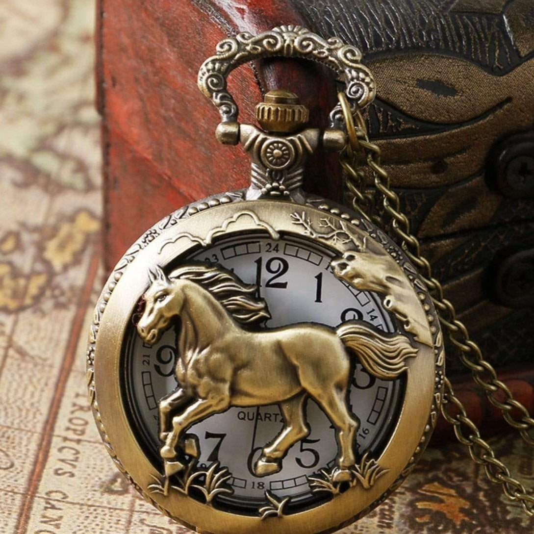 Close-up of a bronze-colored horse pocket watch with a chain, presented on an aged map and ornate box.