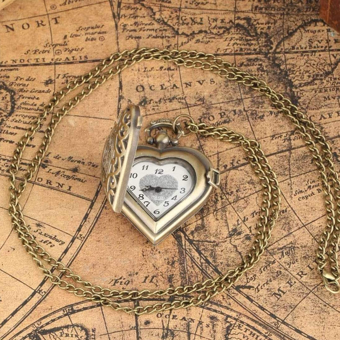 A vintage heart-shaped locket necklace with a bronze chain sits on an antique map background.