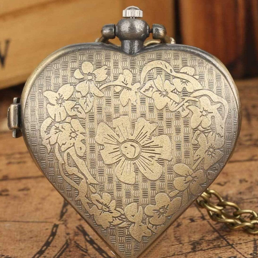 Close-up of a heart-shaped, antique gold-tone pocket watch with floral engravings.
