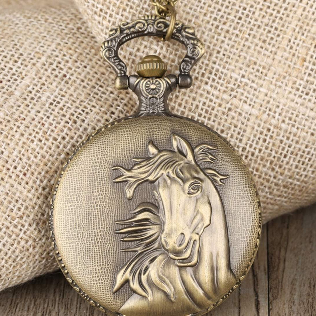 Close-up of an antique-bronze pocket watch with a raised horse relief on the cover, draped over a burlap sack and a wooden surface.