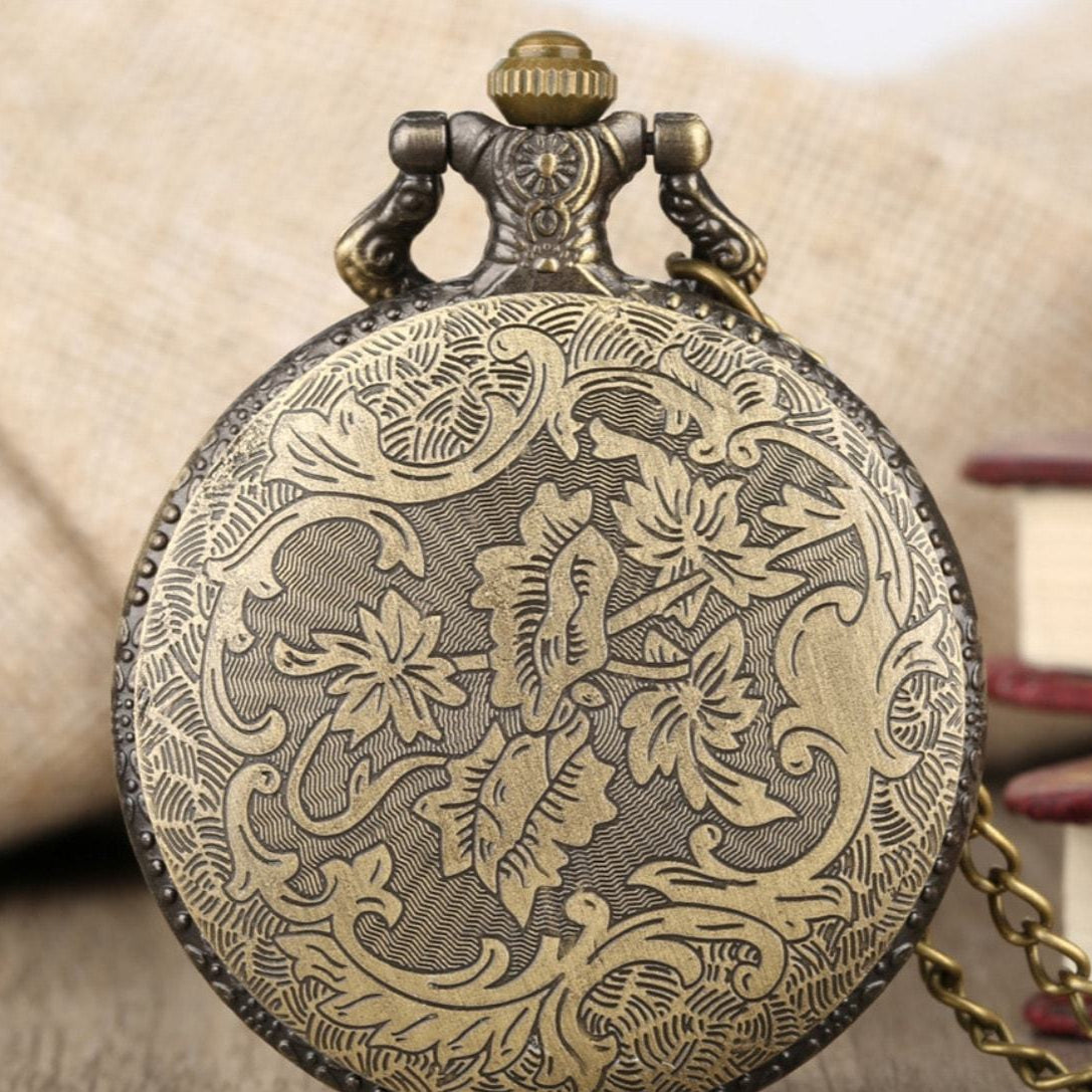 Close-up of a brass pocket watch with floral engraving.