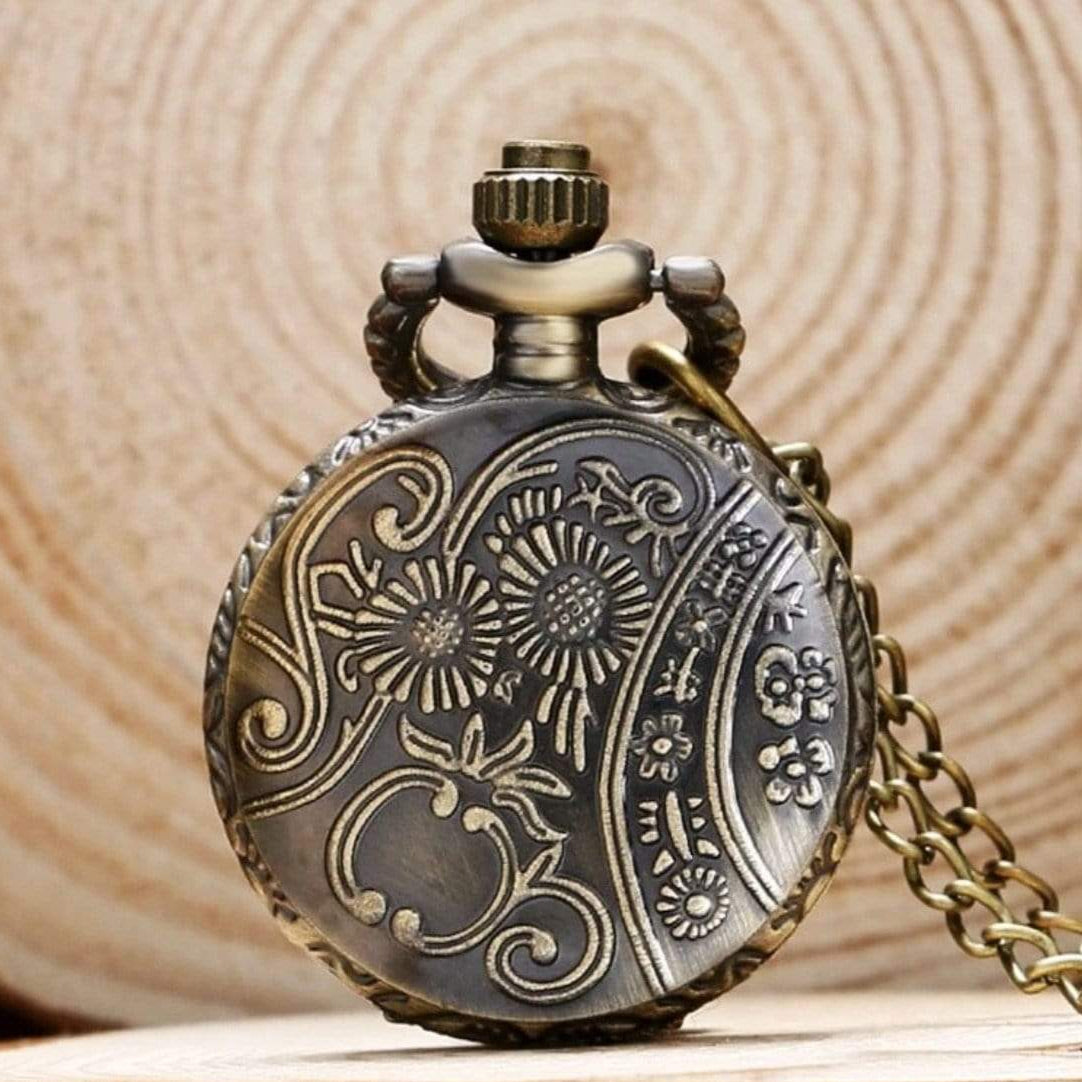 Close-up of an ornate, bronze-colored pocket watch with floral patterns.