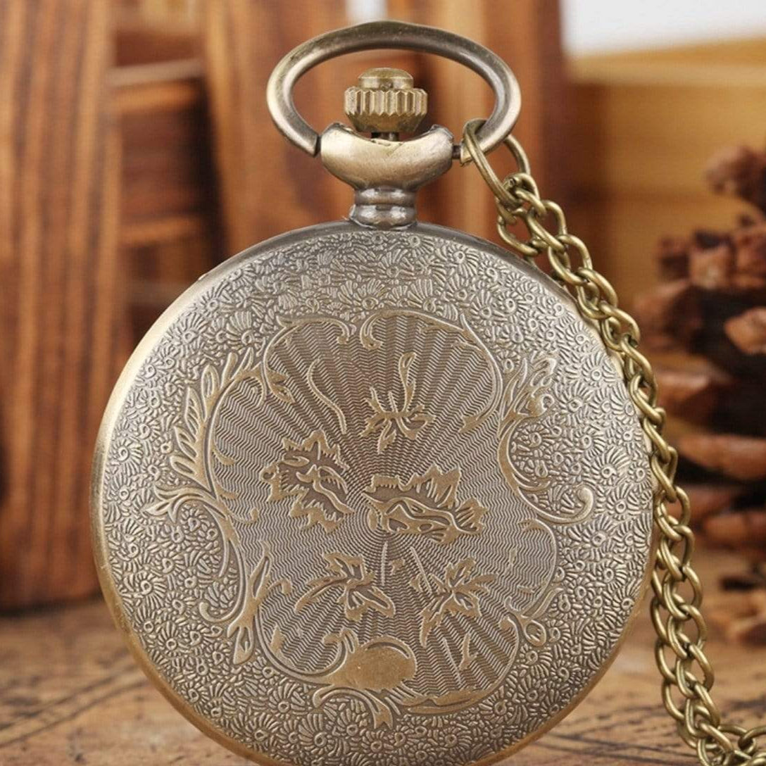 Close-up of a bronze pocket watch with an ornate floral design and chain.

