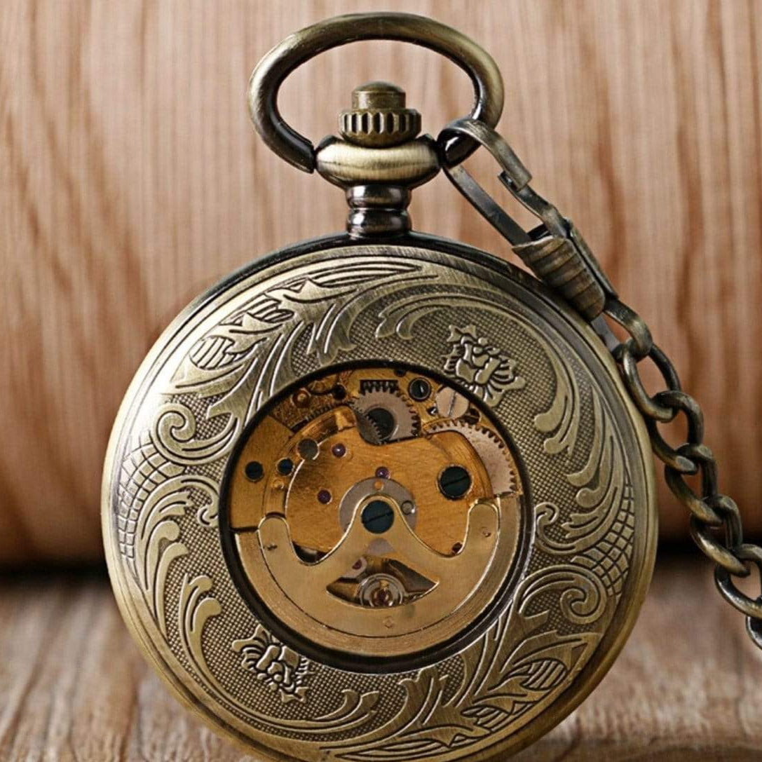 Bronze-colored pocket watch with ornate carvings and a visible gear mechanism.
