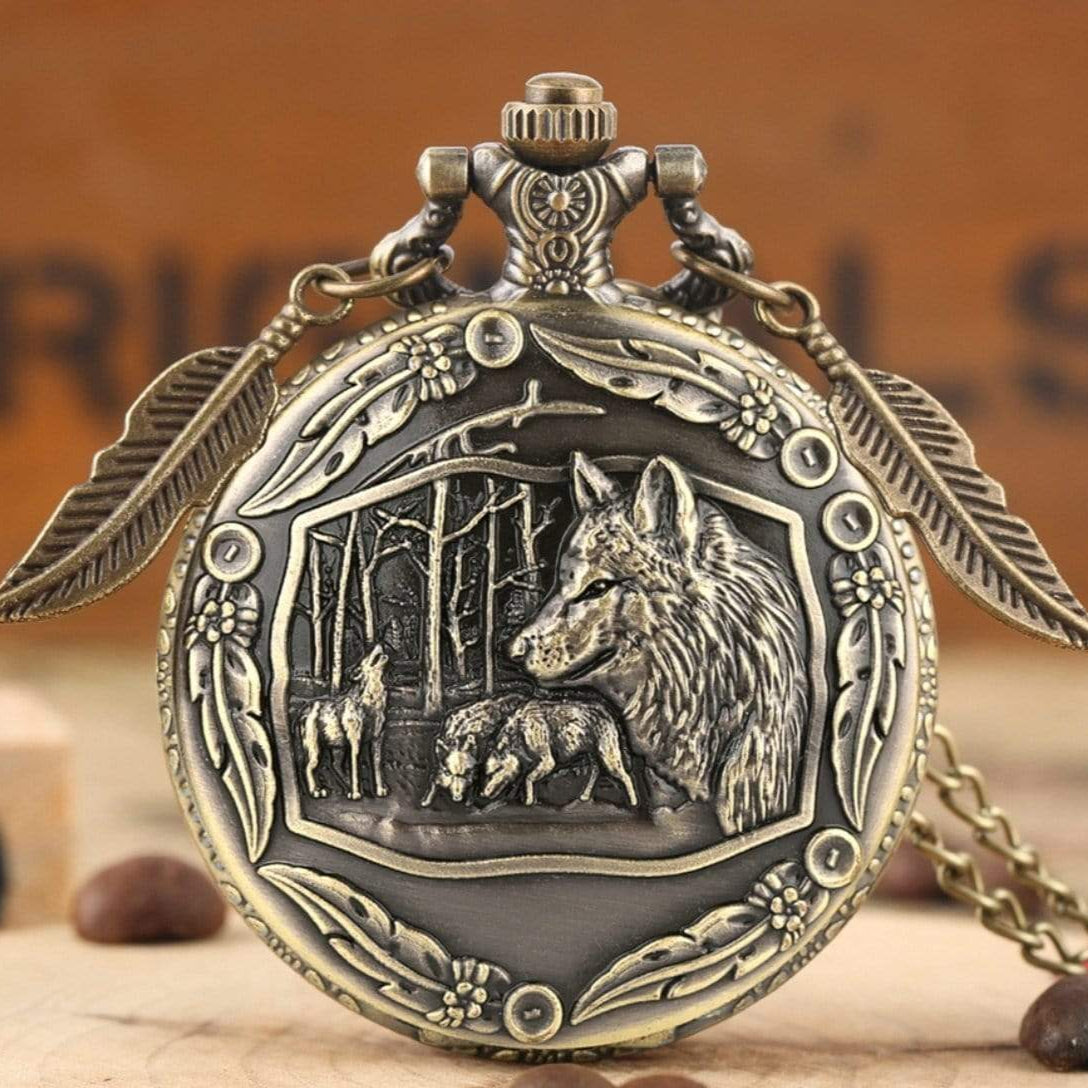 Close-up of an antique bronze pocket watch featuring a wolf and forest scene.