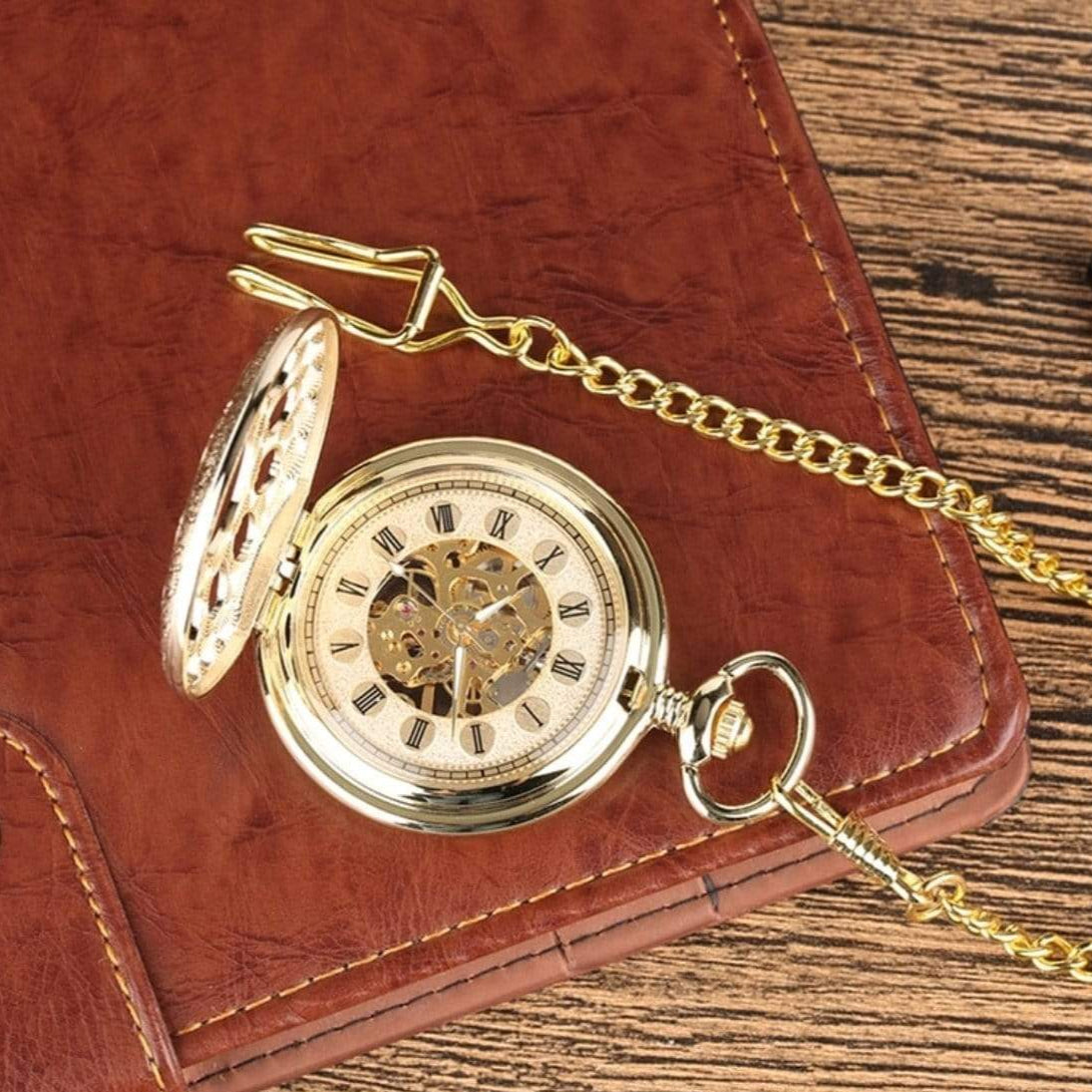 Gold pocket watch with chain on a brown leather case.
