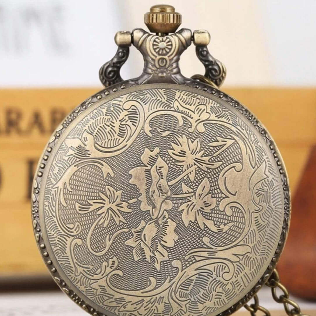Close-up of an antique-looking bronze pocket watch with floral engravings. 
