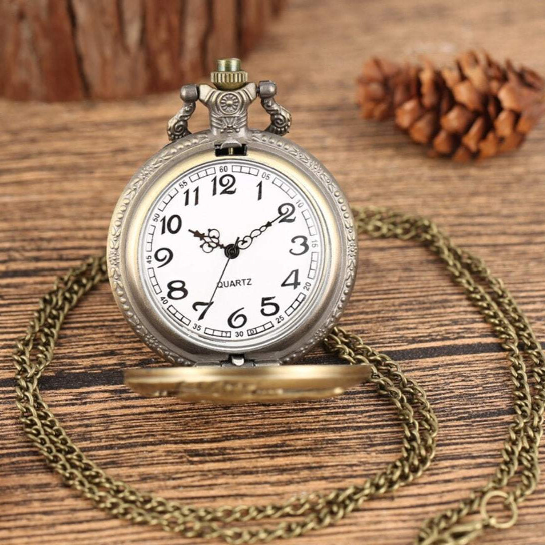 Vintage pocket watch with bronze chain on wooden surface.