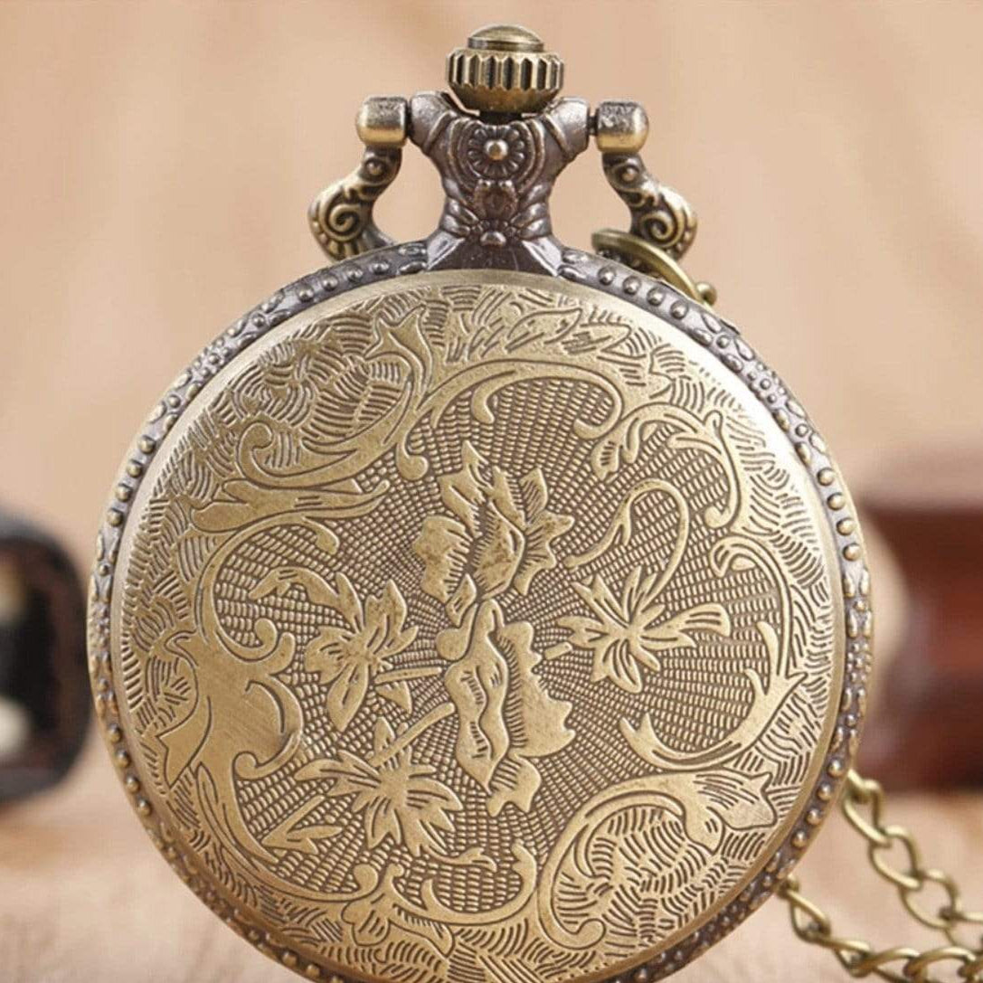 Antique brass pocket watch with floral design.