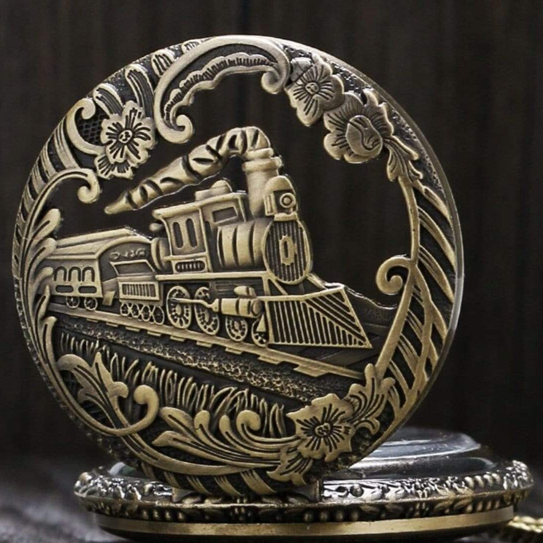 Close-up of an ornate, gold-colored pocket watch featuring a train.
