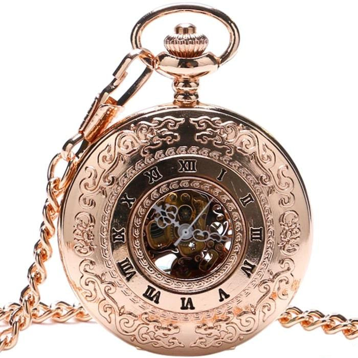 Close-up of a gold pocket watch with Roman numerals, an ornate design, and a chain. 
