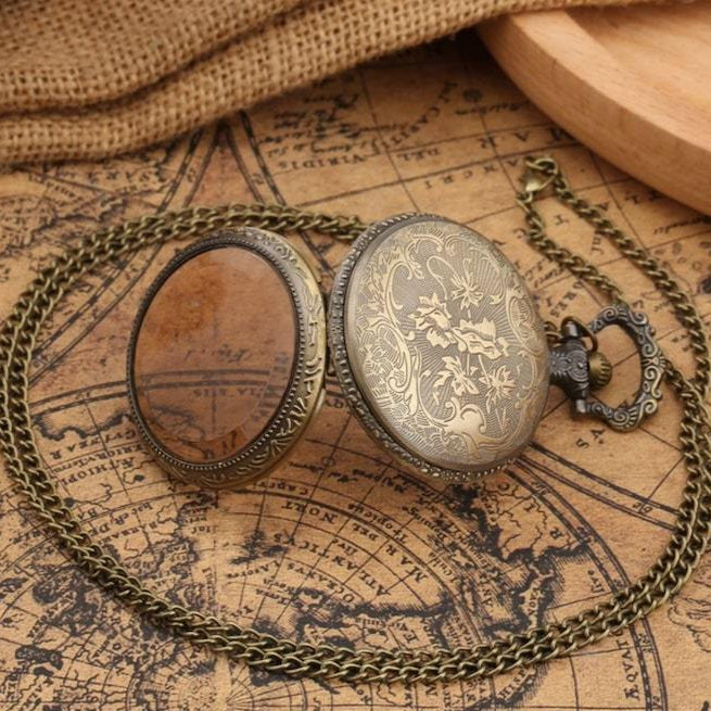 Vintage-style bronze pocket watch with intricate floral design and chain, displayed open on an antique map background.