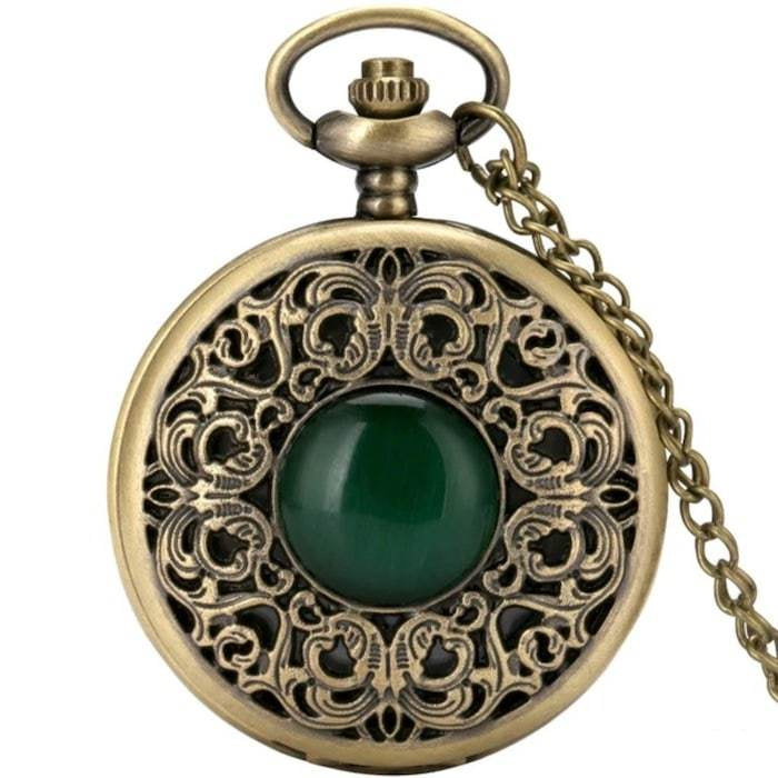 Close-up of an antique-looking gold pocket watch with a green center stone and chain.