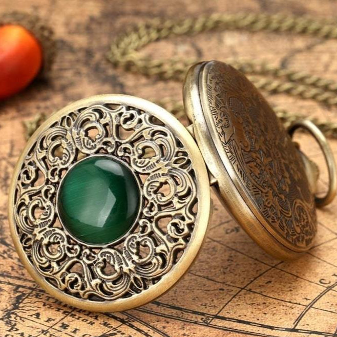 Close-up of an antique gold pocket watch with green stone on a map.