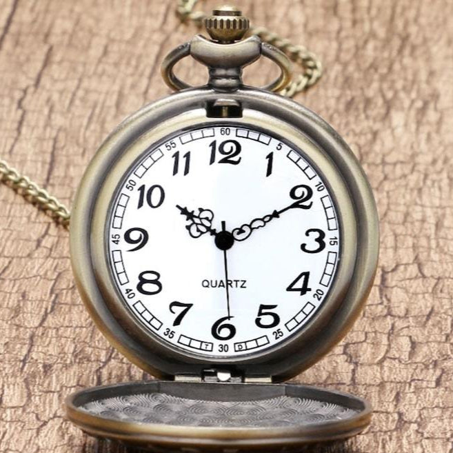 A close-up shot shows an open antique bronze pocket watch with a white face, black numbers, and "quartz" printed at the bottom, set against a wood-grain background.