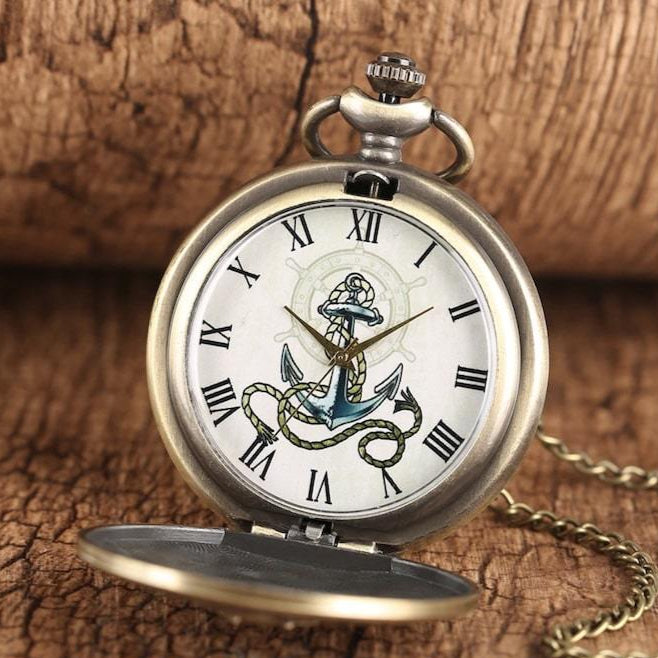 Antique brass pocket watch with nautical anchor design.
