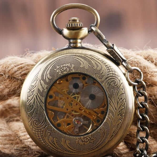 Close-up of an antique, bronze-colored pocket watch with visible gears, resting on a brown rope.