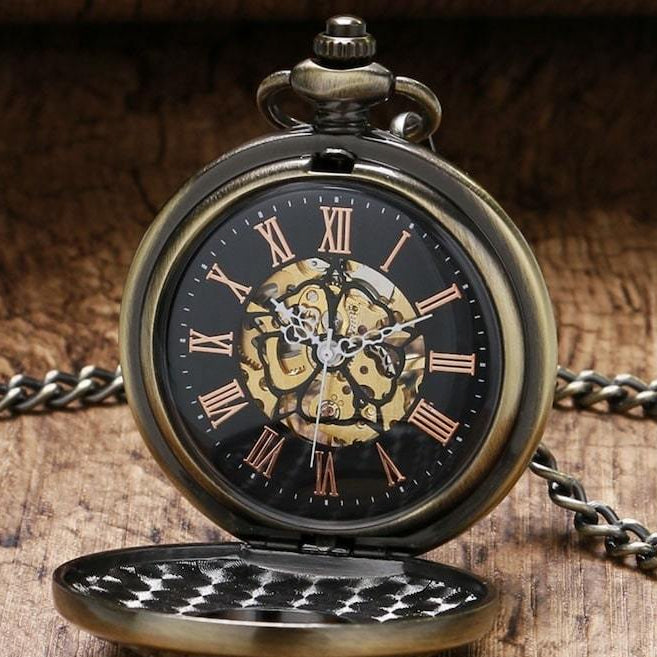 Close-up of an open, bronze-colored pocket watch with Roman numerals and a black face. A chain is attached.