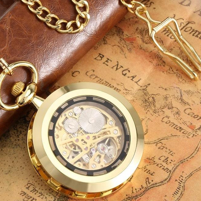 Close-up of a gold pocket watch with visible gears on a vintage map.
