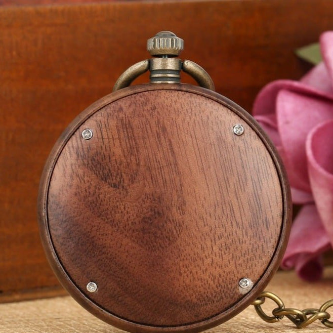 A close-up image of a wooden pocket watch with metal accents, chain, and winder.