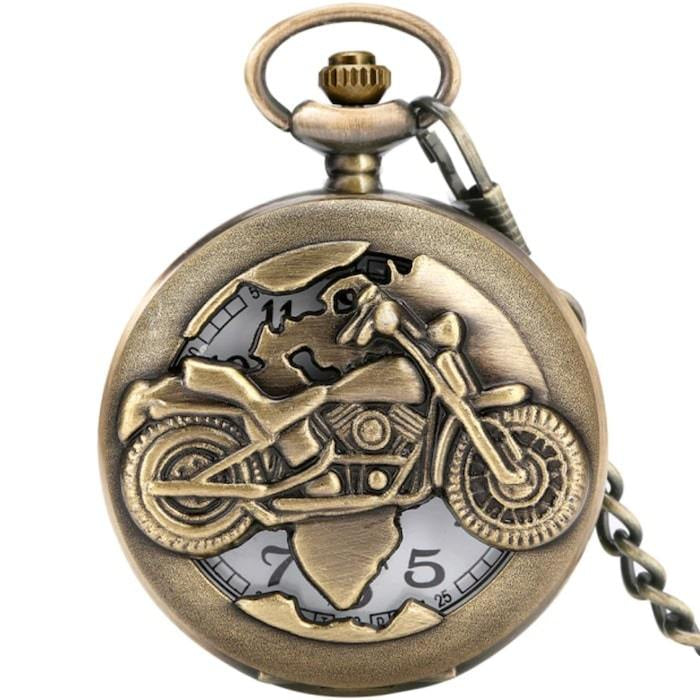 Close-up of an antique gold-tone pocket watch with a motorcycle design on the front.